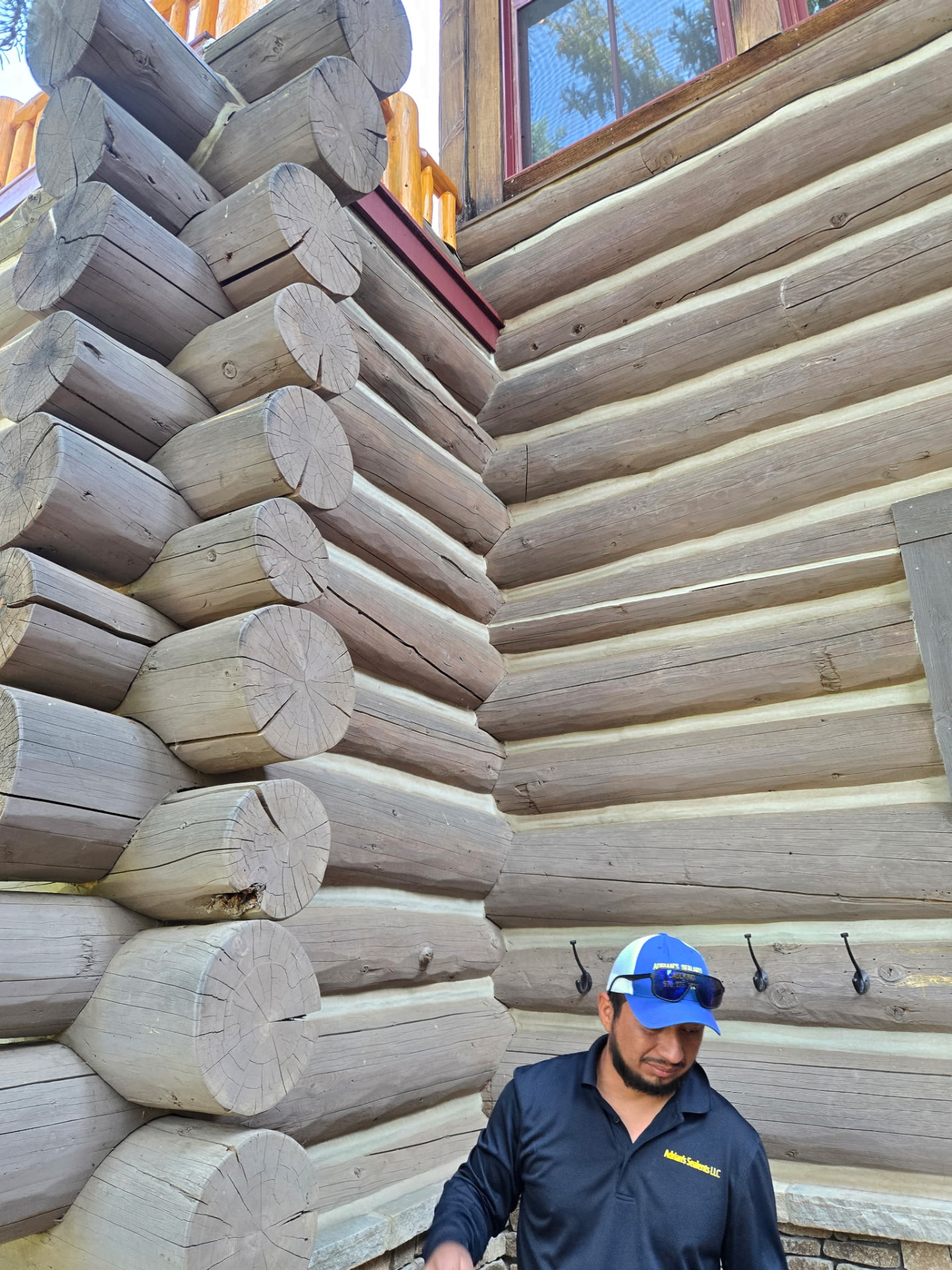 Adrian's Sealants crew member at a freshly chinked log home corner