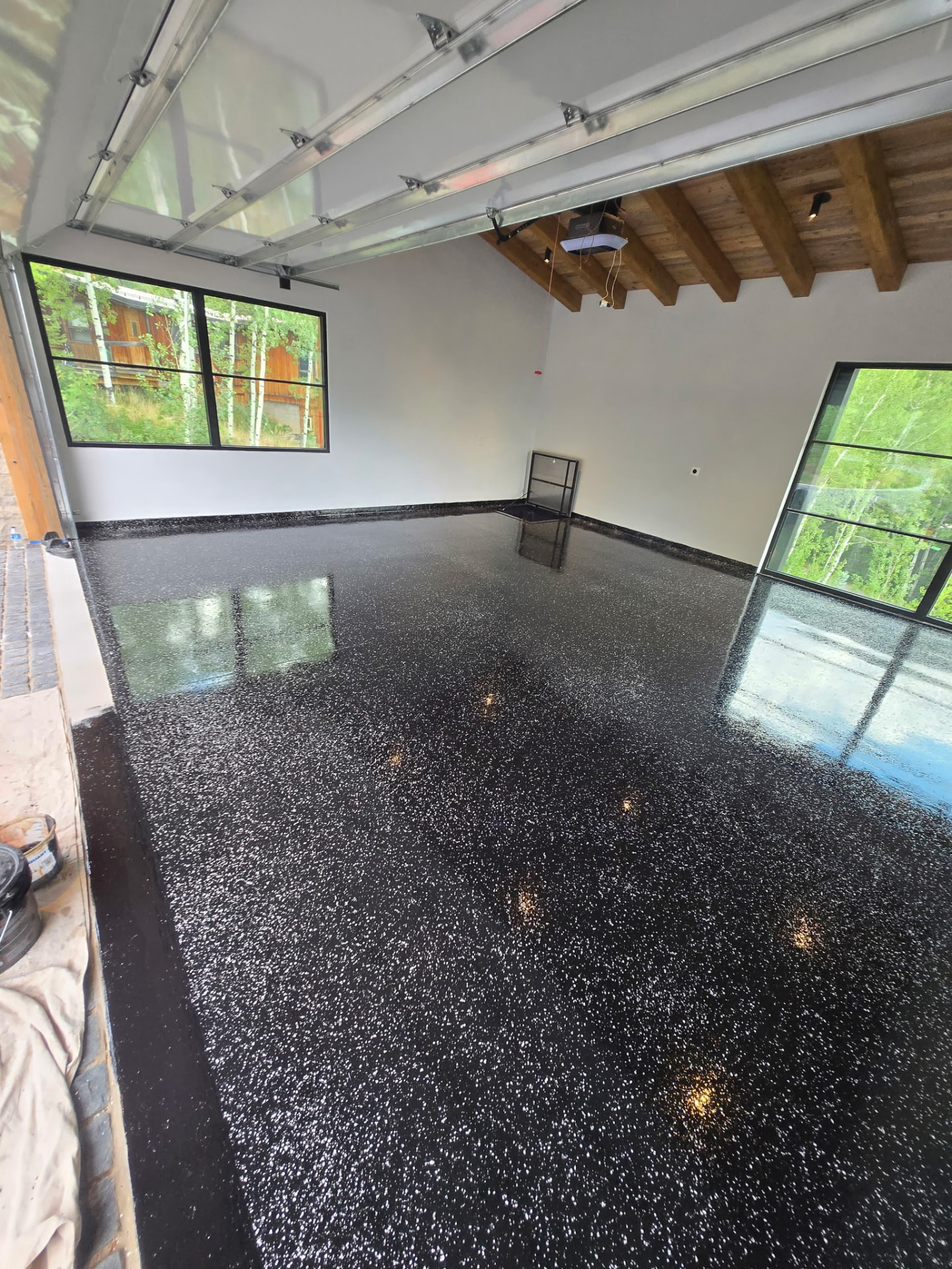 Finished black epoxy flake garage floor with glass garage doors