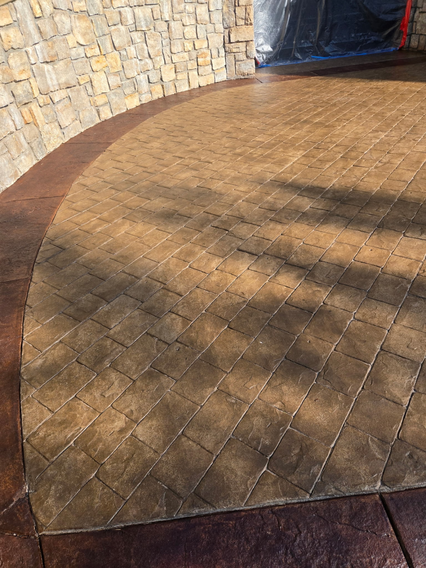 Detailed view of stamped concrete patio with stone wall