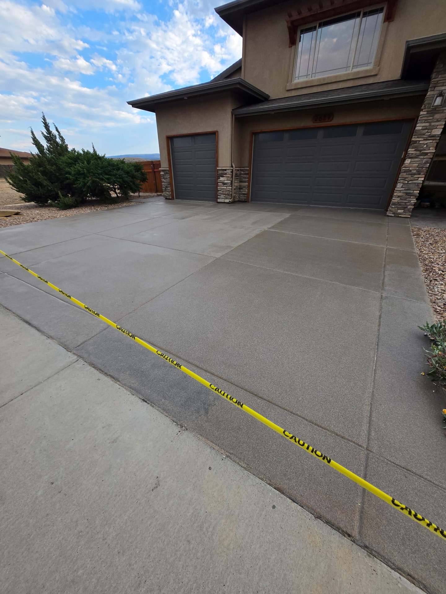 Newly sealed concrete driveway with caution tape at a Colorado home