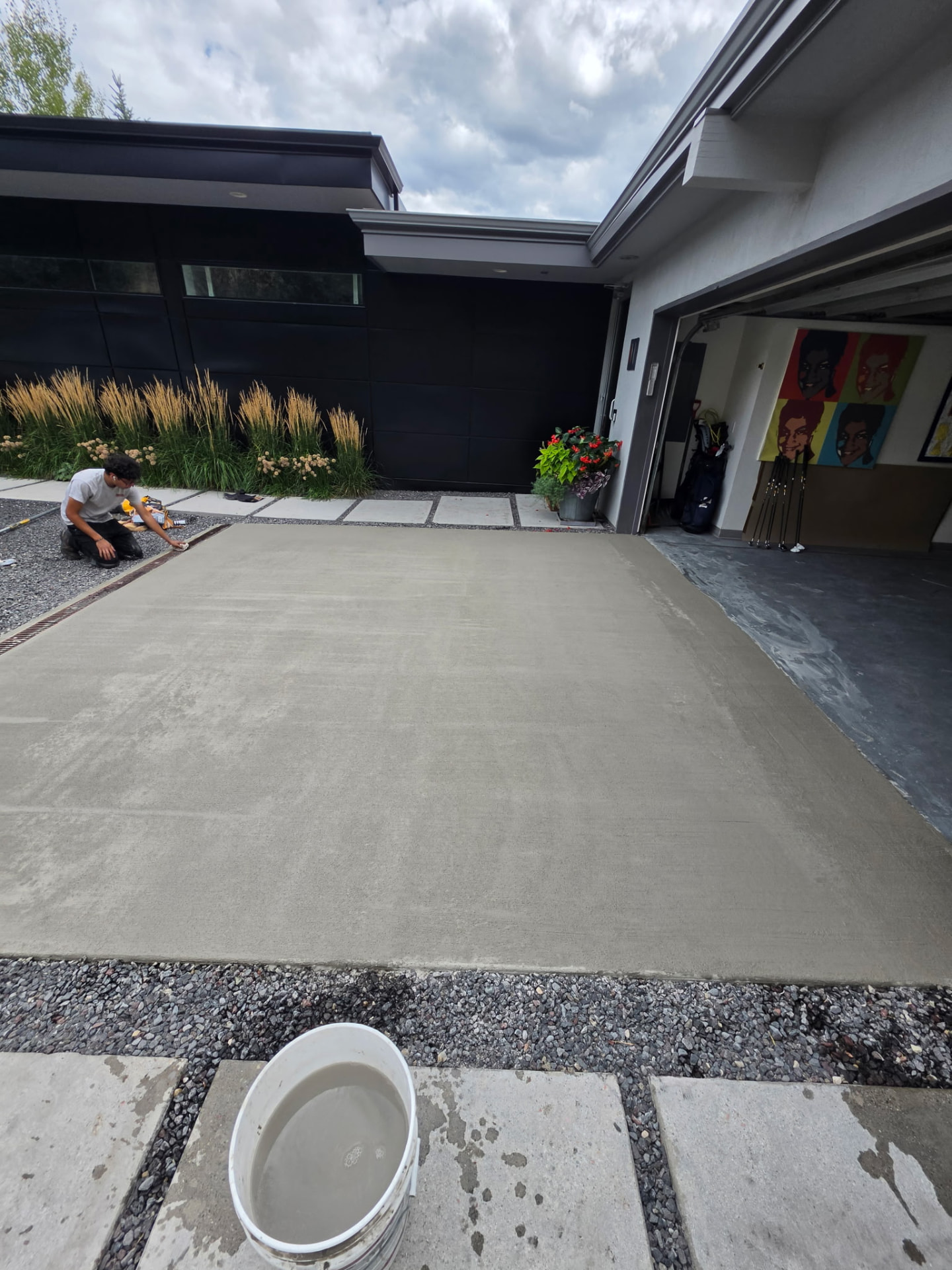 Technician finishing a resurfaced concrete driveway apron at a modern home
